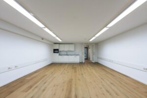 Moderne, lege ruimte aan de Prins Hendrikkade met houten vloer, ingebouwde keuken en witte wanden.